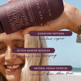 Person holding a bottle of NAK Hair shampoo with product features highlighted