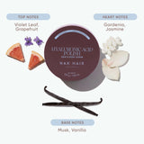 A cosmetic product presentation for NAK HAIR Hyaluronic Acid Polish Hair & Body Scrub. The round jar is dark plum purple, surrounded by illustrative graphics of grapefruit slices, white flowers, vanilla beans, and text labels detailing the fragrance notes: 'The Fragrance More than Routine' with 'Top Notes' and 'Heart Notes' and 'Base Notes' below.