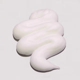White, creamy swirl on a light gray background milk_shake Lifestyling Volumizing Foam