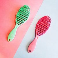 Green and pink hairbrushes on a pink and gray gradient background